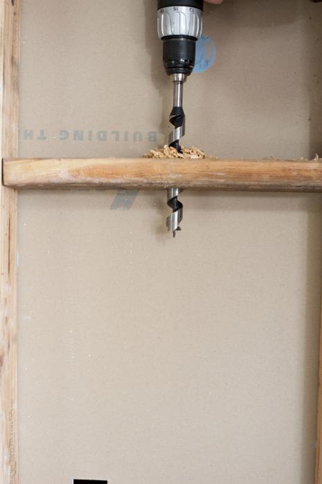 Free Stock Photo: Drilling a vertical hole for wires in stud wall of new built house, viewed in close-up with copy space