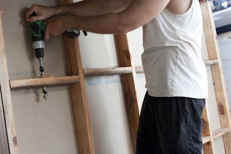 Free Stock Photo: Man drilling a wooden stud wall with electric drill during a house construction