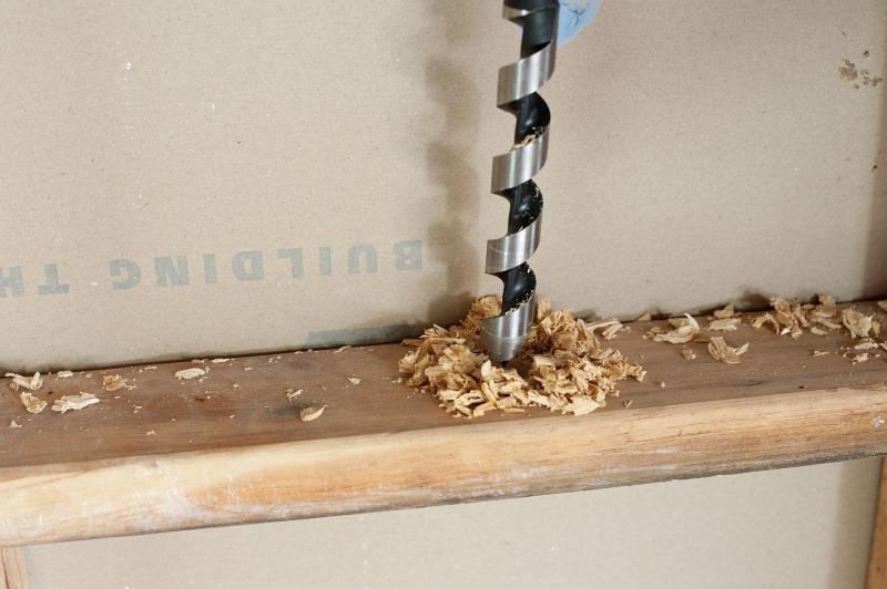 Free Stock Photo: Close up on a drill bit drilling a wooden frame in a stud wall with surrounding saw dust