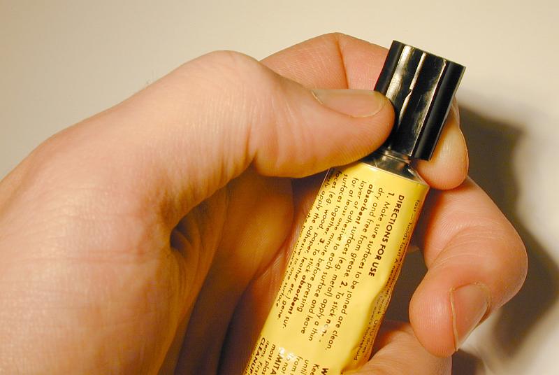 Free Stock Photo: Man holding a closed tube of glue in his hand loosening the cap with his fingers in a close up view