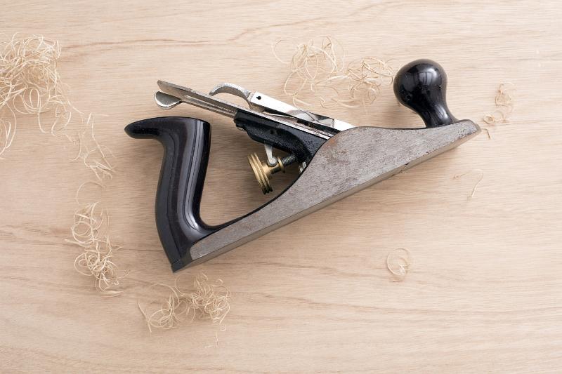 Free Stock Photo: Vintage hand plane tool on its side sitting on the table among wooden shavings