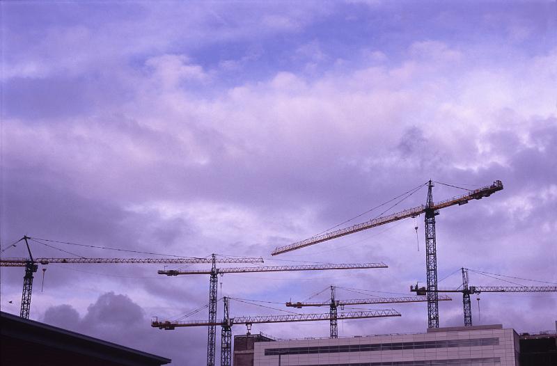 Free Stock Photo: Large urban building project or development with six tall industrial cranes silhouetted against a colorful purple sky at sunset above high-rise buildings