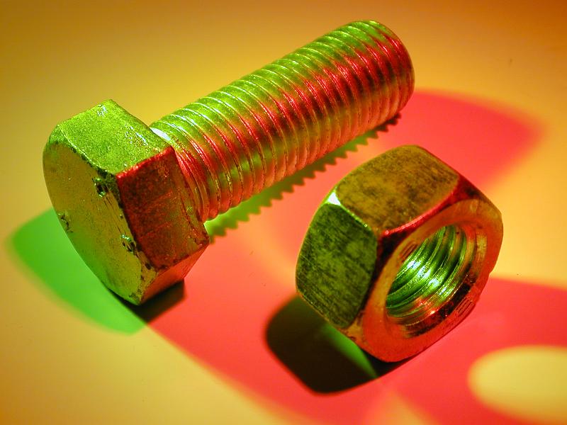 Free Stock Photo: New metal bolt and nut in green and red lights on yellow surface, viewed in close-up from high angle
