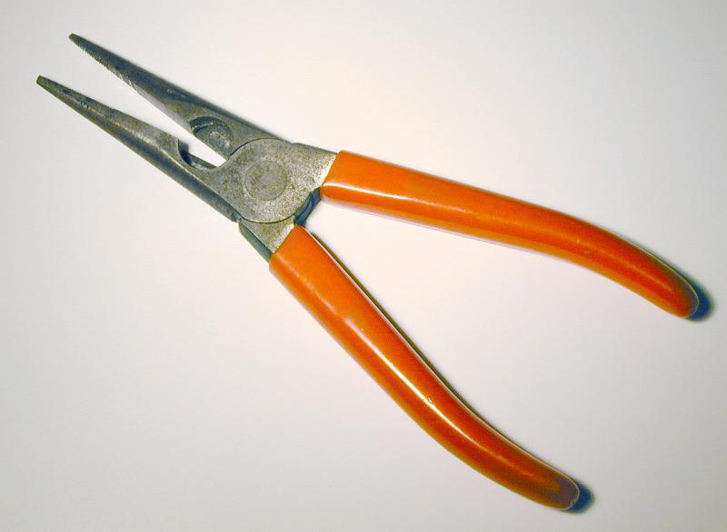 Free Stock Photo: Pliers with red handles framed diagonally and viewed in close-up on white surface background