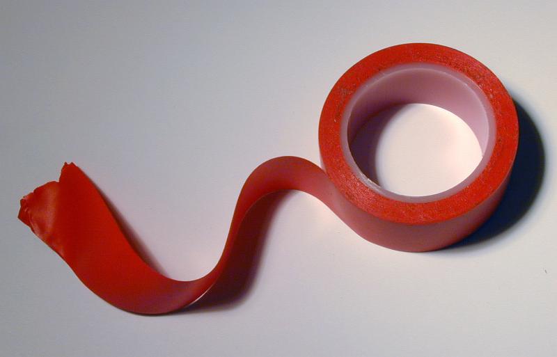 Free Stock Photo: Red insulating tape with wavy unrolled end viewed in close-up from above on grey background