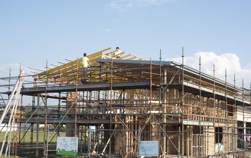 Free Stock Photo: Process of building timber frame house with scaffolding installed round. Two men construction workers during installing a lathing