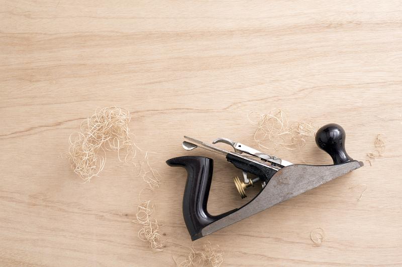 Free Stock Photo: Woodworkers plane with sawdust on wood panel with woodgrain pattern viewed from above