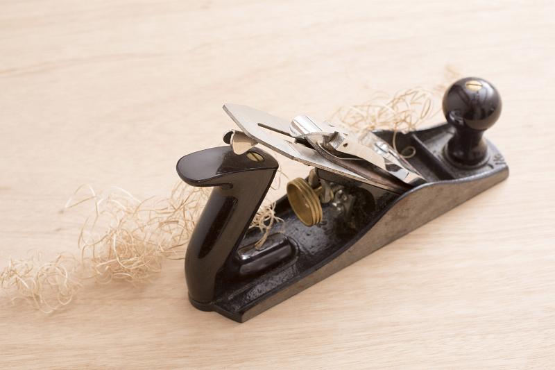 Free Stock Photo: Old-fashion woodworking carpenters plane tool in close-up with wooden shavings on table surface