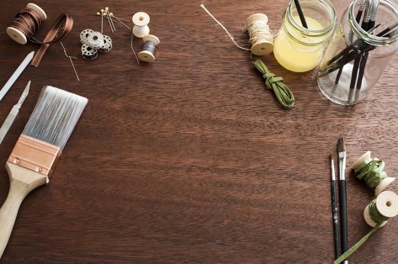 Free Stock Photo: Assorted arts and crafts tools scattered around the edges of wooden desk surface background