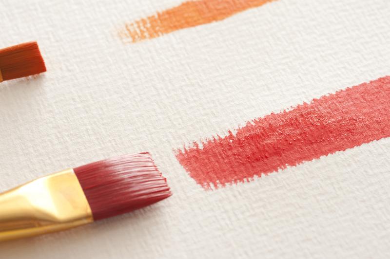 Free Stock Photo: Extreme close up view on orange and red paint strokes from medium and large paint brushes over textured white paper