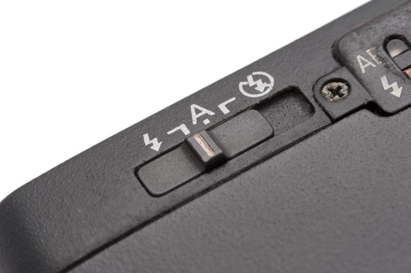 Free Stock Photo: Extreme close up of flash mode on switch for black portable compact camera over white