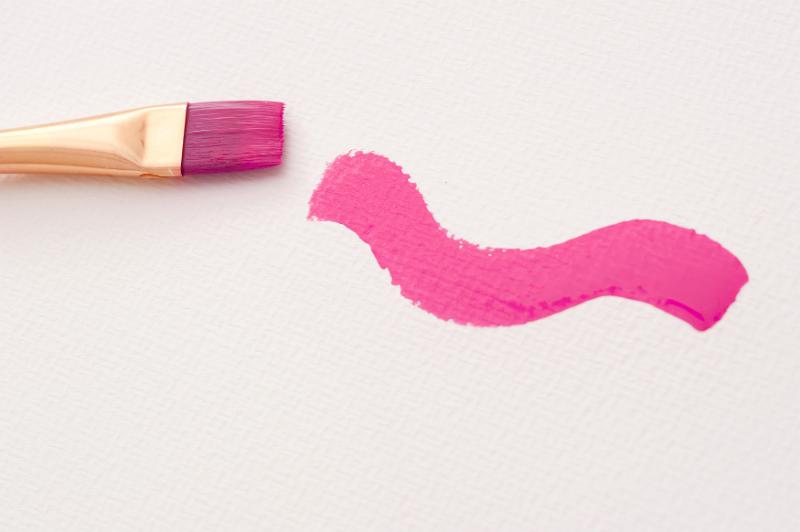 Free Stock Photo: Close up view of medium size brush next to pink paint swirl over white canvas textured paper