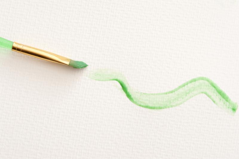 Free Stock Photo: Paint brush stroke in green squiggly line on textured paper canvas