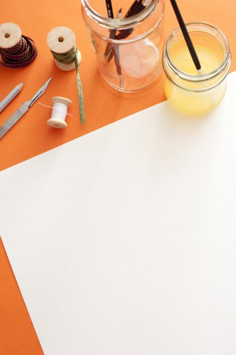 Free Stock Photo: Blank white canvas paper with copy space under spools, knife, brushes and paint on the top edge