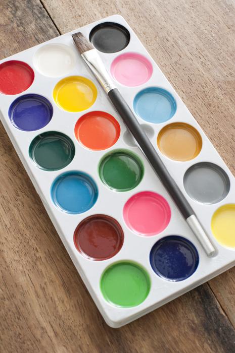 Free Stock Photo: New box of watercolor paints and paintbrush lying open on a wooden desk displaying the range of colors in round pots, high angle view