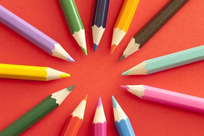 Free Stock Photo: Ring of various sharpened colored pencil tips pointing toward each other over bright red background