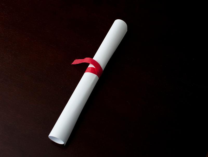 Download image of Rolled diploma tied with ribbon Free Stock Photo: A rolled diploma or document, tied with a red ribbon, over black background