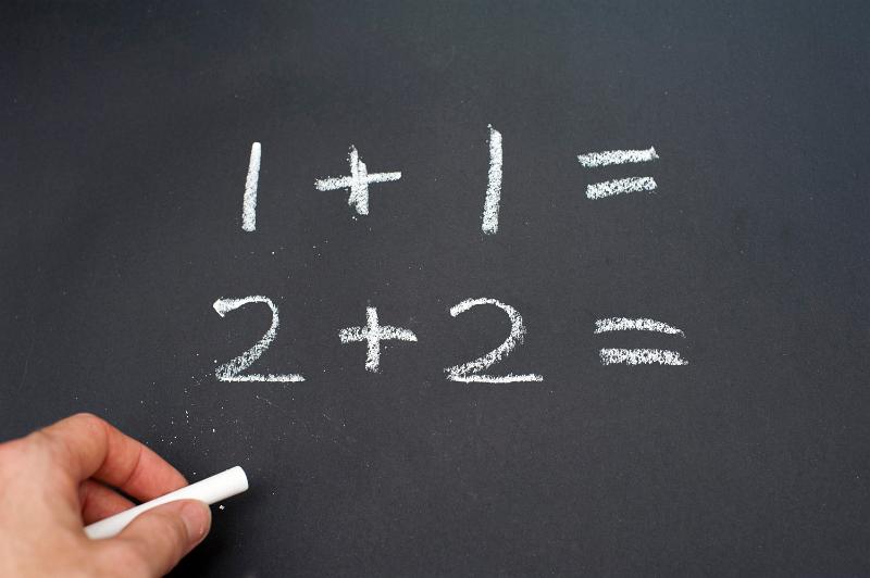 Free Stock Photo: Left-handed person writing numbers using white chalk.