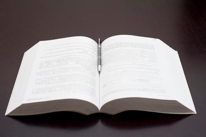 Free Stock Photo: Studio closeup of an open book with a pen resting in the centre, on a black background