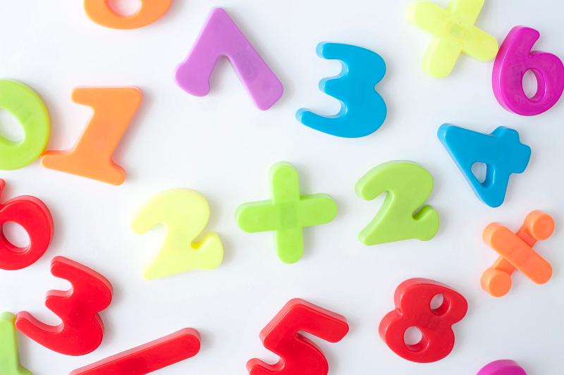 Free Stock Photo: Preschool maths education concept with colourful plastic numbers and symbols scattered on a white surface