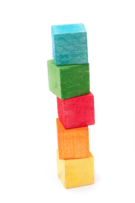 Free Stock Photo: Wooden toy building blocks, in bright colours over white background, stacked in a tower