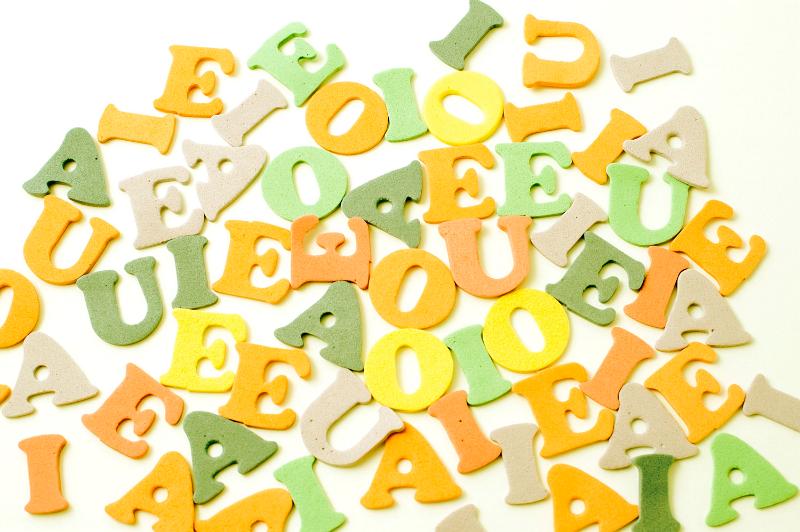 Free Stock Photo: Scattered colorful vowels of the alphabet in yellow, green, cream and orange tones