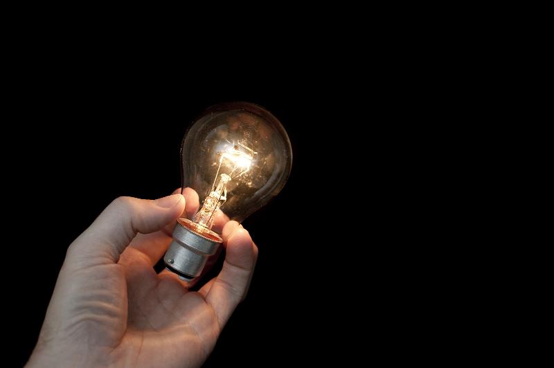 Free Stock Photo: a hand holding a glowing light bulb with a black background