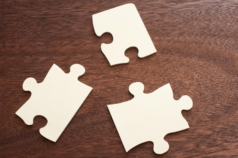 Free Stock Photo: Close up of three blank jigsaw puzzle pieces placed in a triangle shape on a wood table