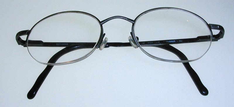 Free Stock Photo: Close up on pair of simple folded thin metal frame eyeglasses over gray background