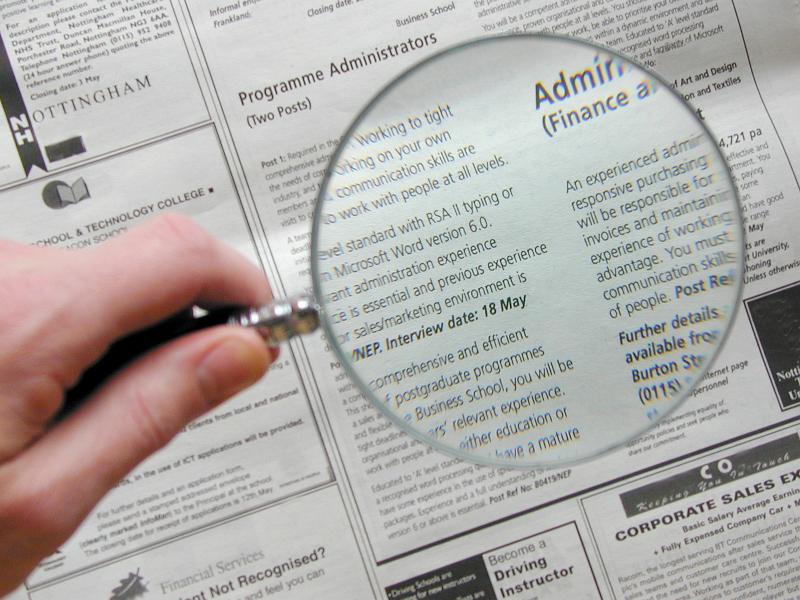 Free Stock Photo: Man using a magnifying glass to read the fine print on a newspaper advertisement with a view through the lens of the enlarged print