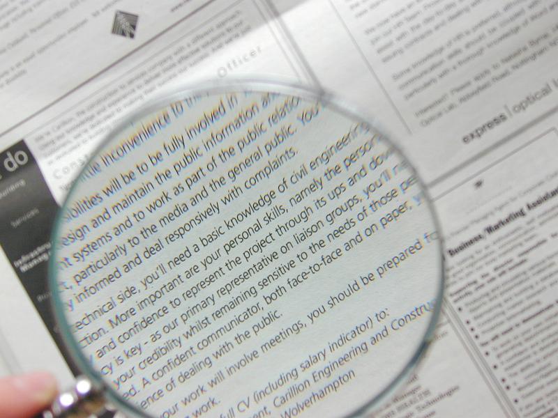 Free Stock Photo: Man using a magnifying glass for small print to magnify the text, view through the glass lens of the enlarged type