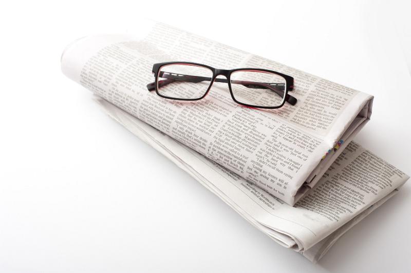 Free Stock Photo: Pair of generic reading glasses on two folded newspapers over a white background with copy space arranged diagonally