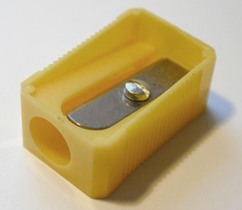 Free Stock Photo: Simple yellow plastic pencil sharpener with a close up view on the blade at the top for school or office supplies