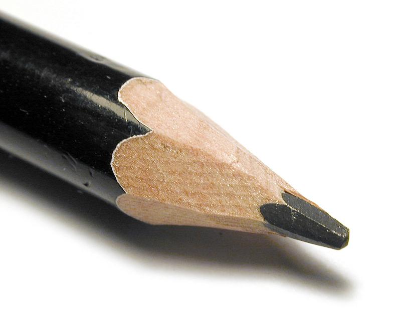 Free Stock Photo: Sharpened black wooden pencil point in a close up macro view over white with shadow
