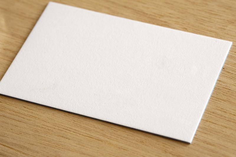 Free Stock Photo: Plain white textured card on a wooden desk with copy space for your text viewed at an oblique angle