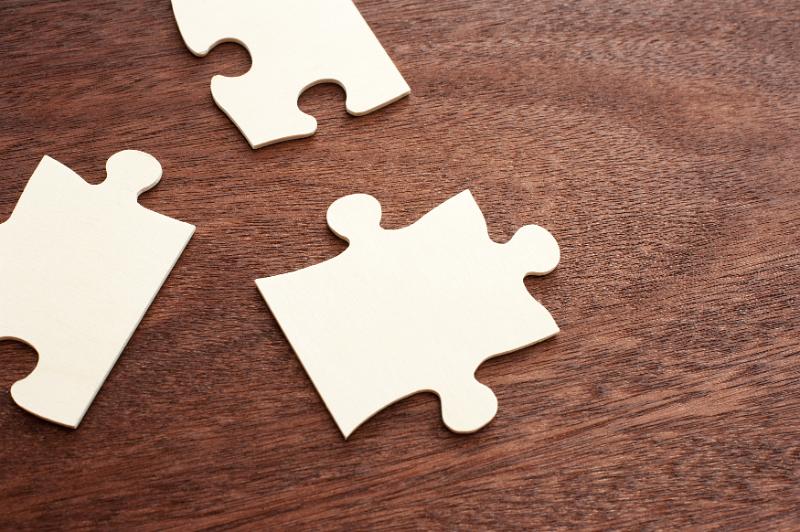Download image of Cropped set of three blank puzzle pieces Free Stock Photo: Cropped set of three blank unassembled puzzle pieces with copy space on dark wood grain table
