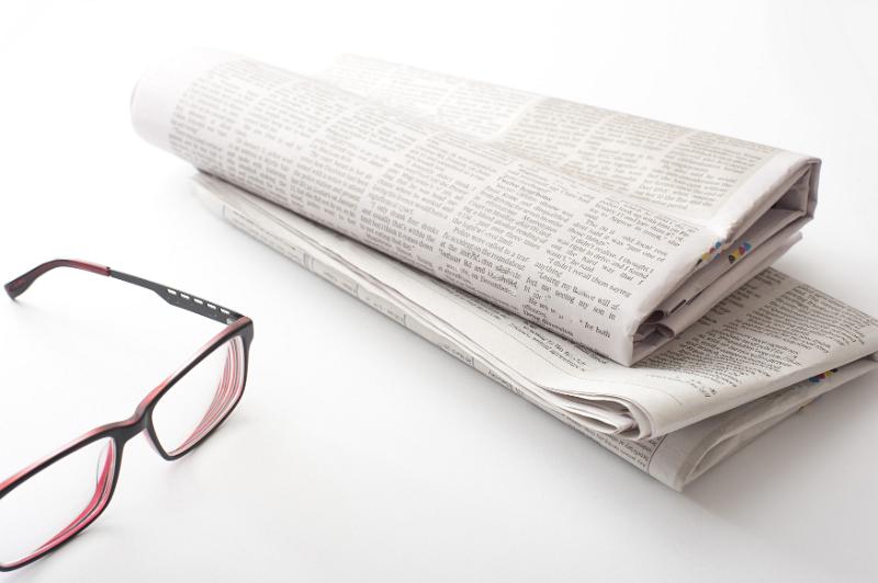 Free Stock Photo: Folded newspaper with reading glasses on a white background with copy space conceptual of relaxation