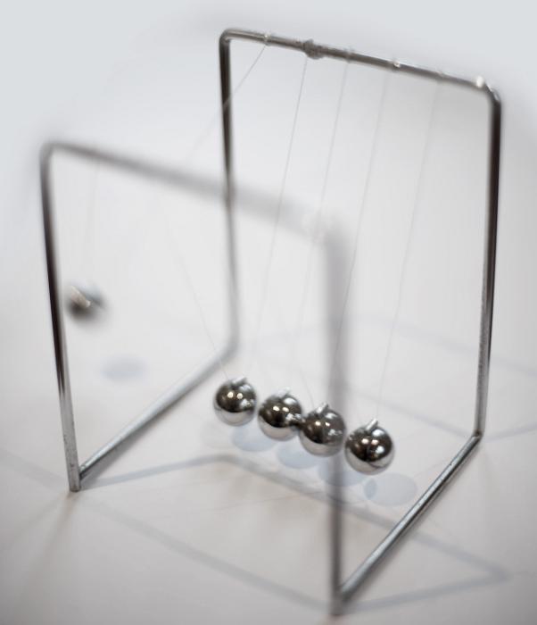 Free Stock Photo: Newtons cradle executive desk toy with five suspended metal balls which transmit motion when one end ball is raised and released