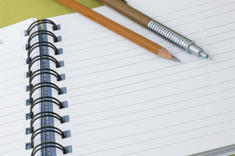 Free Stock Photo: A mechanical and a sharpened wooden pencil lying on a blank lined page of a notebook