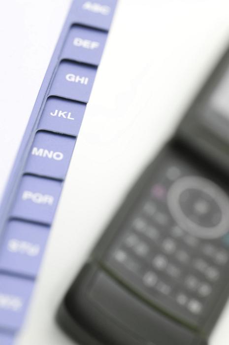 Free Stock Photo: Open cellphone lying on top of an indexed address book ready to dial after the number is located