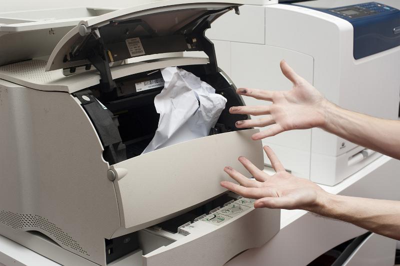 Free Stock Photo: Frustrated person with ink on their hands trying to clear a paper jamb in an office printer