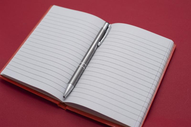 Free Stock Photo: Open lined notebook with a ballpoint pen in the center. There is room to put your message on both pages