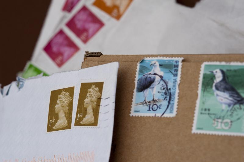 Free Stock Photo: Background of a variety of cancelled UK postage stamps on white and brown envelopes.