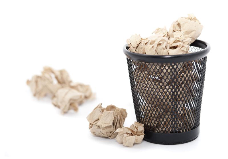 Free Stock Photo: Full office wasterpaper bin full of crumpled discarded paper on a white background with overflow on the floor