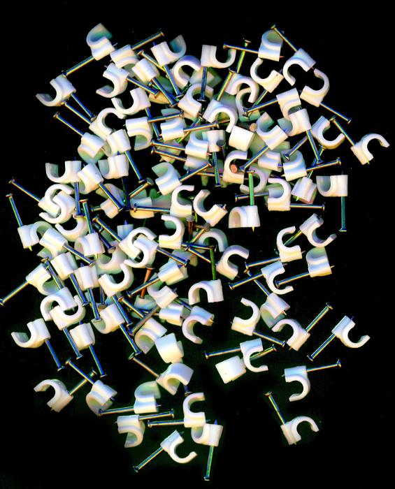 Free Stock Photo: Random scatter of white plastic cable clips for attaching domestic cables and wires to a wall lying on a black background, over head view