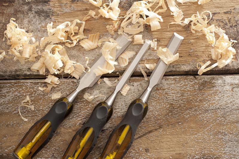 Free Stock Photo: Three sharp woodworking chisels lying on rustic planks with fresh wood shavings conceptual of carpentry and construction